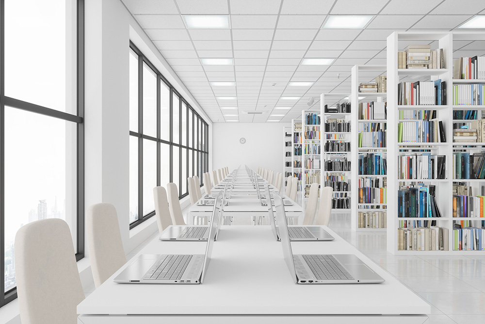 a white room with chairs around a big table with laptops on