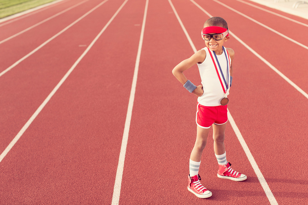 child on athletics track wearing medal
