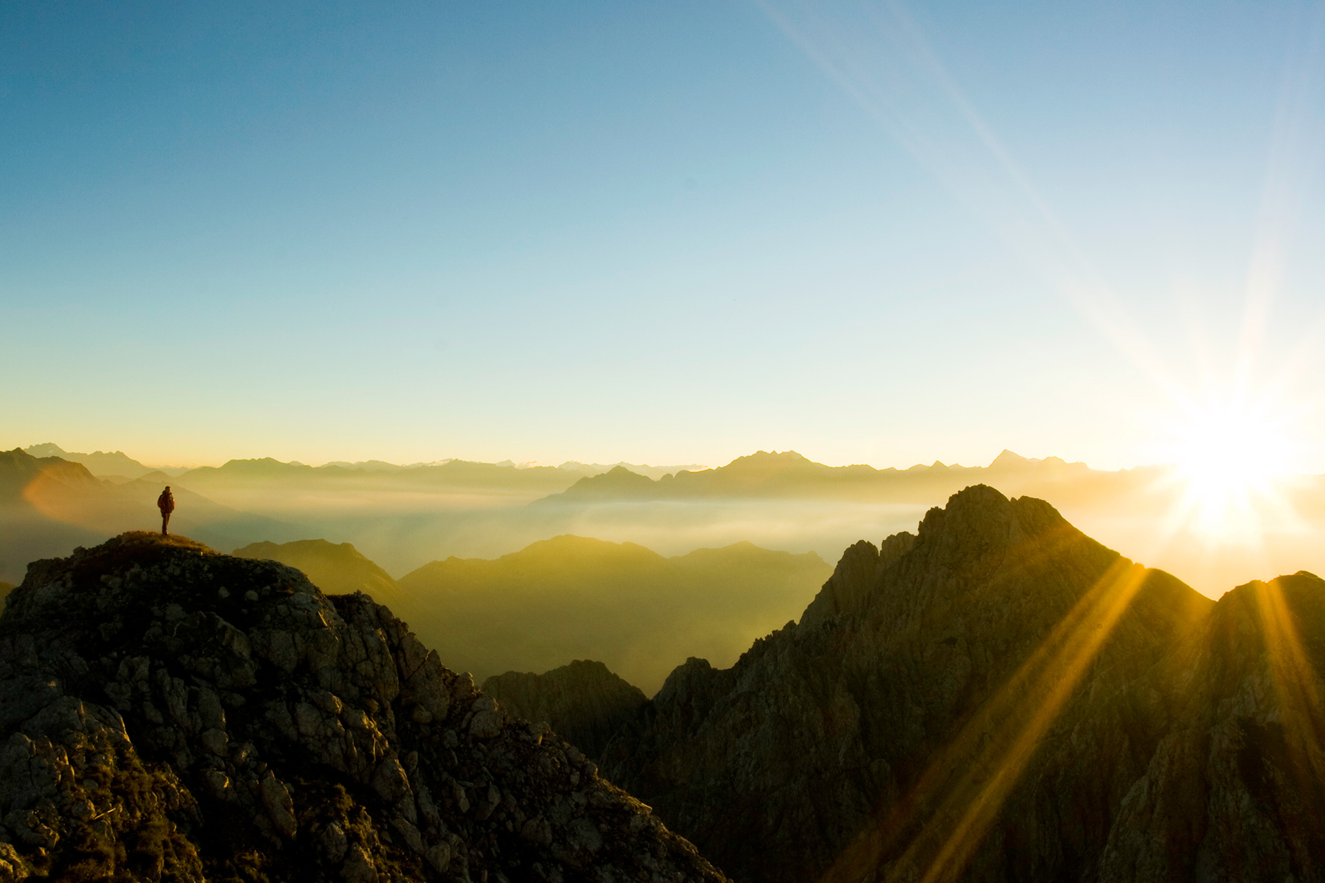 person on mountain watching sunrise
