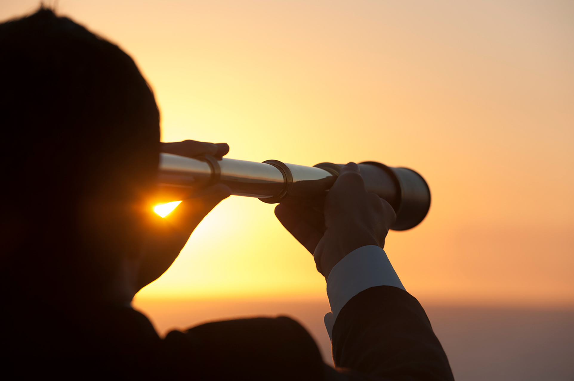 man looking through telescope out to sea