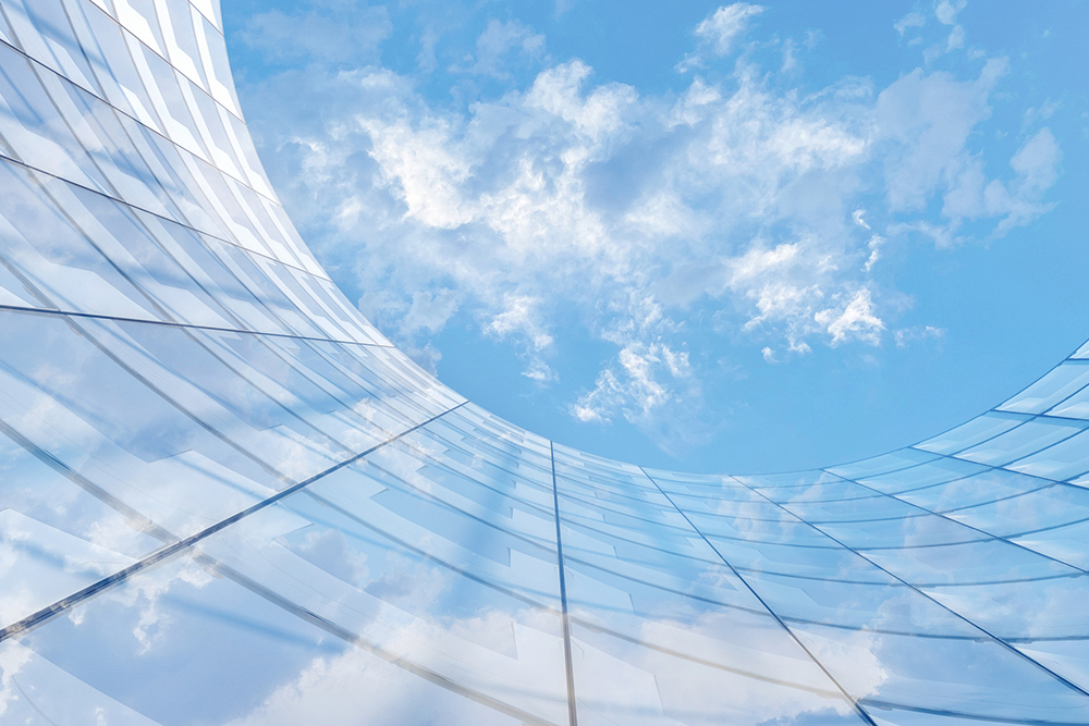 looking up at the exterior of a curved office block with reflective windows